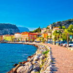 Strandpromenaden i Torbole ved Gardasjøen, med utsikt over sjøen og Brenta-Dolomittene i bakgrunnen | Expa Travel