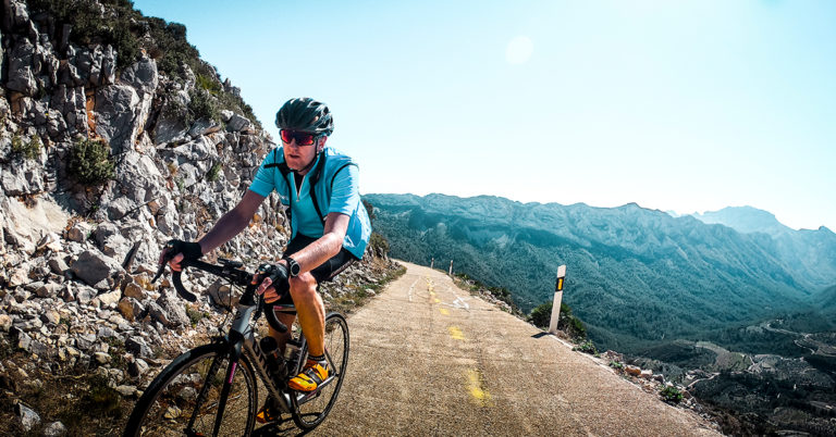 Syklist i blå trøye på vei opp fjellet i Calpe