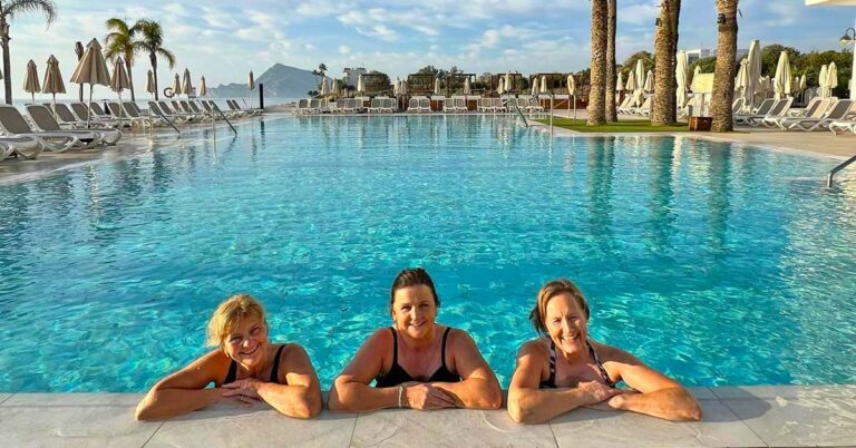 Deltakere i bassenget på Cap Negret, med fjell og palmer i bakgrunnen