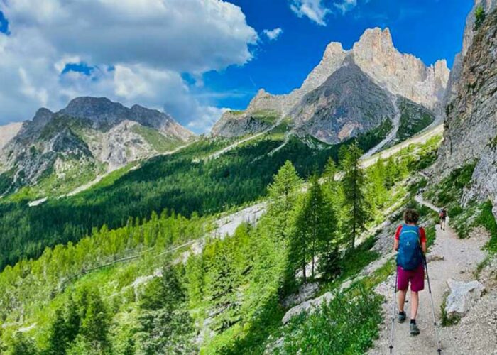 Deltaker med staver på smal sti i Dolomittene
