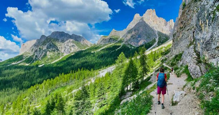 Deltaker med staver på smal sti i Dolomittene