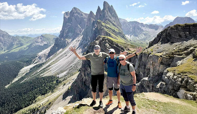Godt Voksne-turer med både kvinner og menn. Dette bildet er av tre menn på toppen av et fjell, med fantastisk utsikt over Dolomittene.