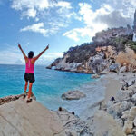 Deltaker med henda i været på en nydelig strand på fotturen Selvaggio Blu