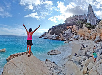 Deltaker med henda i været på en nydelig strand på fotturen Selvaggio Blu