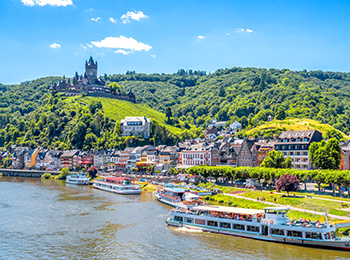 Utsikt over den historiske byen Cochem i Moseldalen med Mosel-elven, vinranker i forgrunnen og Reichsburg-slottet i bakgrunnen