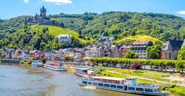 Utsikt over den historiske byen Cochem i Moseldalen med Mosel-elven, vinranker i forgrunnen og Reichsburg-slottet i bakgrunnen